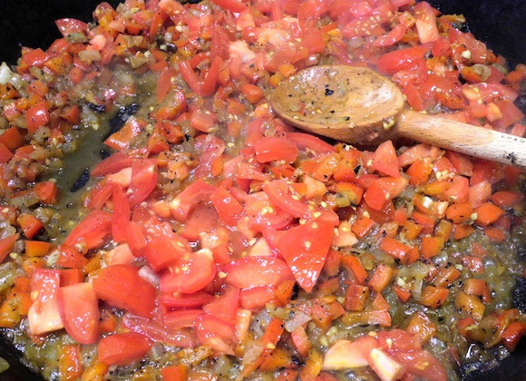 1. Этап. Черная паэлья: 5. Тем временем нарезать небольшими кубиками помидоры и измельчить чеснок. Добавить на сковороду, обжарить пару минут.