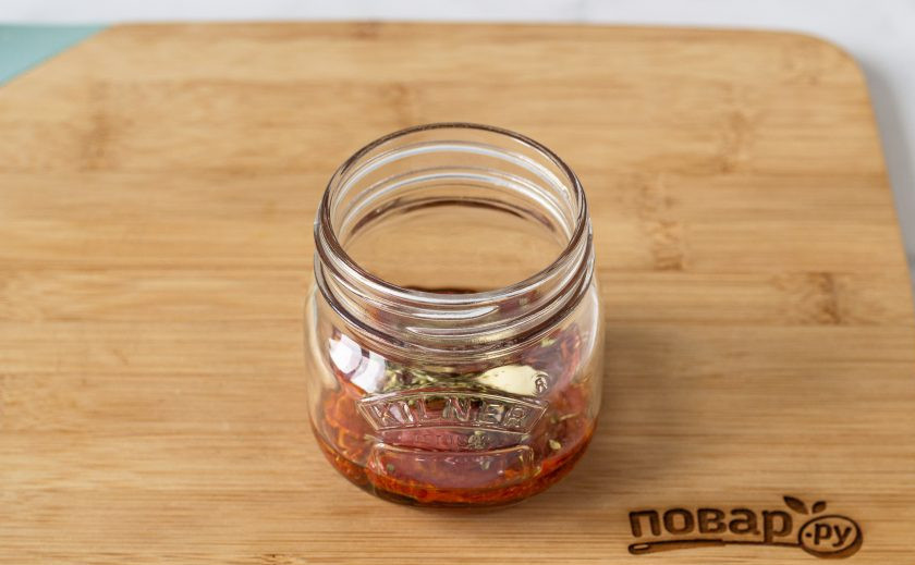 1. Этап. Вяленые томаты в масле: Подготовьте чистую стерилизованную баночку. Выложите слоями томаты, очищенные зубчики чеснока и сушеные итальянские травы.