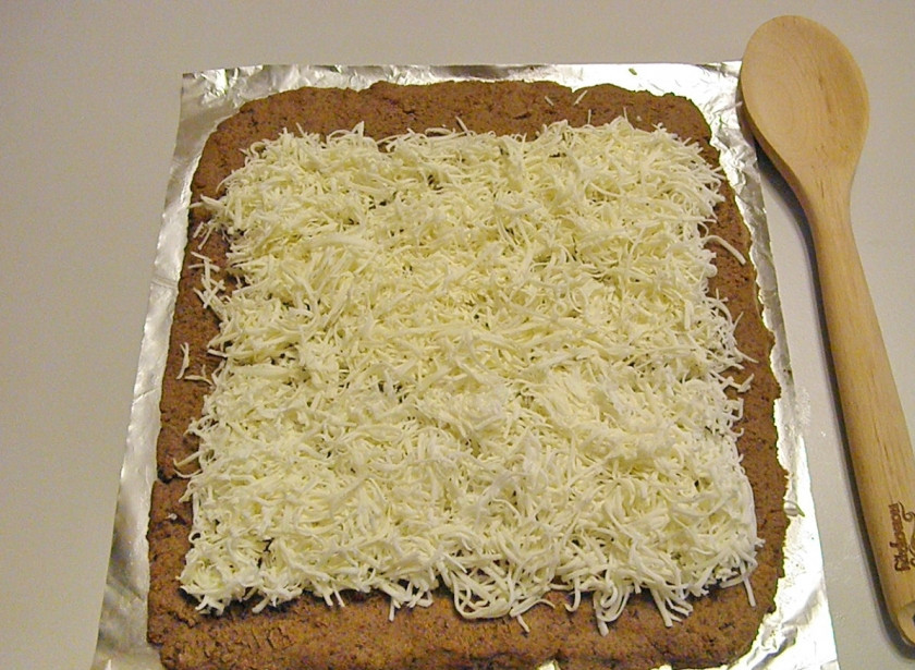 1. Этап. Печеночный рулет: Сверху распределите тертый плавленый сыр. Только отступите от ближнего края 1-2 см., а от края дальнего — 2-3 см.