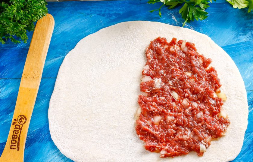 1. Этап. Чебуреки в казане: Разделите тесто на несколько частей, раскатайте каждую из них в округлый пласт, подпыливая рабочую поверхность мукой. На половину теста выложите приготовленную начинку, но не толстым слоем, а размазывая ее. Если слой начинки будет слишком плотным, то она не успеет внутри приготовиться!