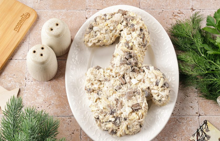 1. Этап. Новогодний салат Варежка на год Змеи: Выложите салат на плоскую тарелку и придайте ему форму варежки с выглядывающей из неё головой змеи.