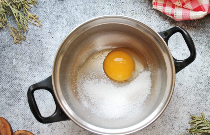 1. Этап. Яичный пунш: Разделите яйцо на белок и желток, белок в этом рецепте нам не понадобится. В кастрюлю или сотейник с толстым дном выложите сахарный песок, ванильный сахар и желток.