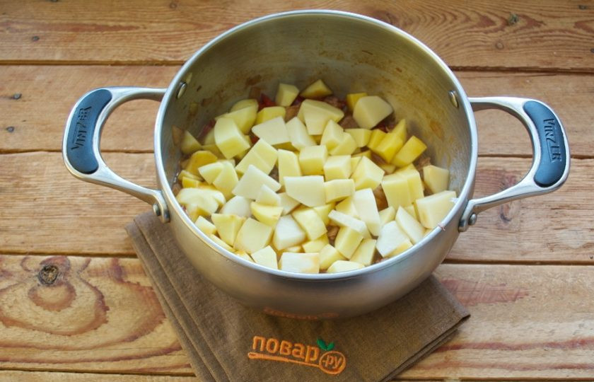 1. Этап. Цыганский острый суп: Очистите картофель. Нарежьте кубиком и добавьте в кастрюлю.