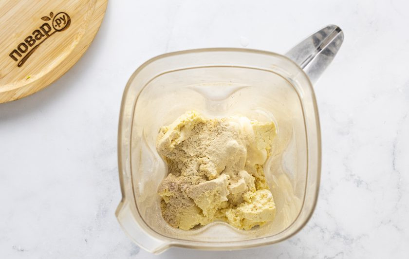 1. Этап. Веганская запеканка из кабачков с тофу: Для основы измельчите в блендере тофу вместе с постным майонезом, пищевыми дрожжами, каррагинаном и черной солью до однородности. Затем постепенно добавьте такое количество воды, чтобы консистенция напоминала очень густую сметану.