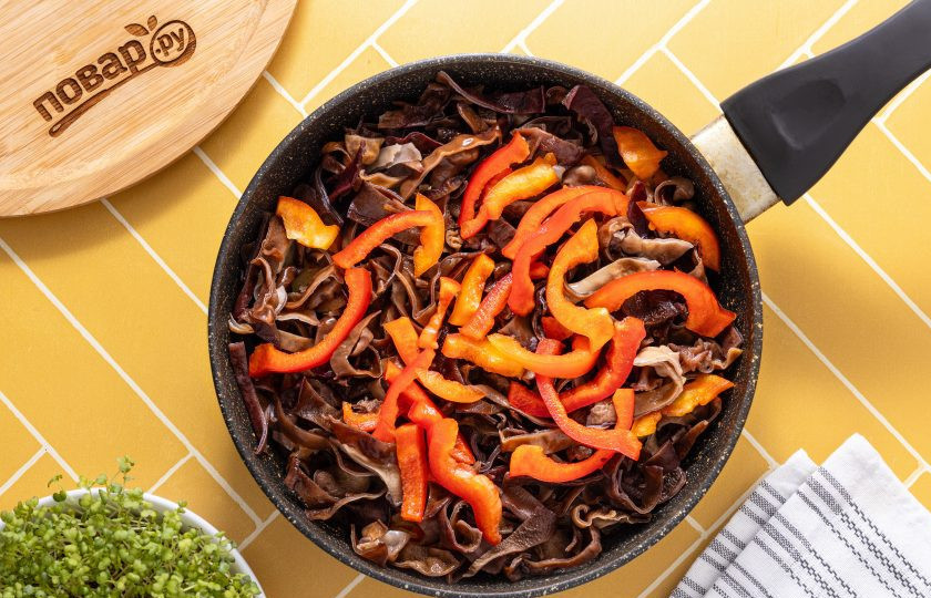 1. Этап. Салат из фунчозы и китайских древесных грибов: Добавьте подготовленные древесные грибы и нарезанный соломкой болгарский перец. Готовьте все вместе еще 3-4 минуты.
