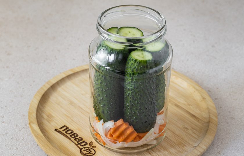 1. Этап. Маринованные огурцы Глобус: На дно чистой банки выложите репчатый лук и морковь. Затем заполните банку огурцами. Добавьте лавровый лист и черный перец горошком.