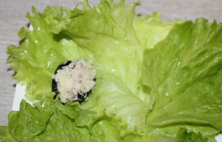 1. Этап. Чернослив фаршированный грецкими орехами: Выложите чернослив на листья салата.