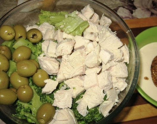 1. Этап. Салат с курицей и брокколи: Теперь вернемся к остывшей курочке. Нарежем её небольшого размера кубиками. Салатные листья промоем, обсушим и порвем руками на любого размера кусочки. К курочке с салатом теперь переложим горошек и брокколи, а также оливки (жидкость, в которой они находились, нужно предварительно слить). Все ингредиенты посолите, можете добавить любимые специи. В отдельной небольшой ёмкости сделаем заправку для салата: для этого смешиваем сметану и горчицу.