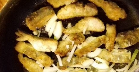 1. Этап. Рыба, жаренная по-восточному: В сковороде разогрейте масло. Рыбу обваляйте в муке. Обжарьте кусочки со всех сторон до золотистого цвета в масле. В конце добавьте лук.