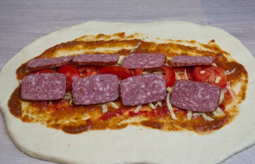 1. Этап. Стромболи: 6. Болгарский перец и помидоры нарежьте и выложите на сыр. Нарежьте колбасу. Данную пиццу делают с копченостями или с ветчиной. Тут вид мясных изделий выбирайте сами. Мясную начинку выложите поверх овощей.