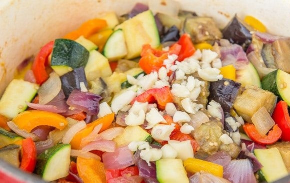 1. Этап. Рататуй из баклажана и цуккини: 5. Далее поставьте средний огонь. Добавьте масло и смешайте все овощи. Сверху насыпьте измельчённый чеснок.