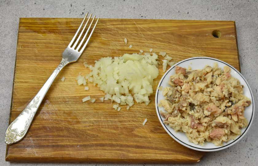 1. Этап. Пасхальный салат с консервированным лососем: Половинку луковицы нарежьте мелким кубиком и залейте кипятком. Оставьте на несколько секунд и отожмите лук от влаги. Консервированную рыбу освободите от костей, и разомните филе вилкой. Для сочности добавьте немного рыбный бульон из консервы.