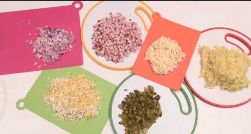 1. Этап. Салат Еловые шишки: 1. Для приготовления блюда отвариваем яйца и картофель, то же проделываем и с филе. Нарезаем все вышеперечисленное, а также — лук и огурцы — мелким кубиком. Сыр натираем на мелкой терке (можно брать твердый или плавленый).