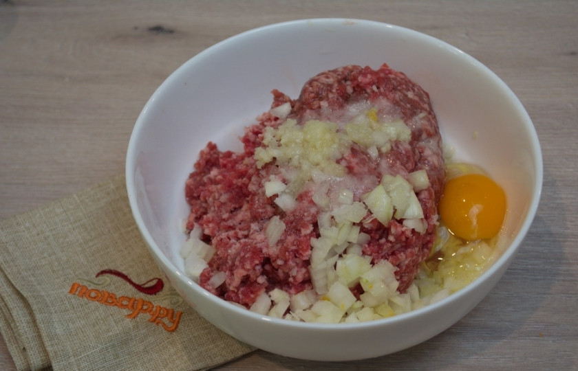 1. Этап. Котлеты под соусом Бешамель: К фаршу добавьте измельченный лук и чеснок.