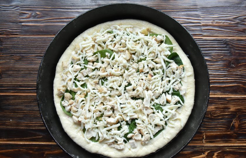 1. Этап. Пицца Альфредо: Сверху на соус выложите половину шпината, часть куриного филе и моцареллу. Края теста смажьте растительным маслом.