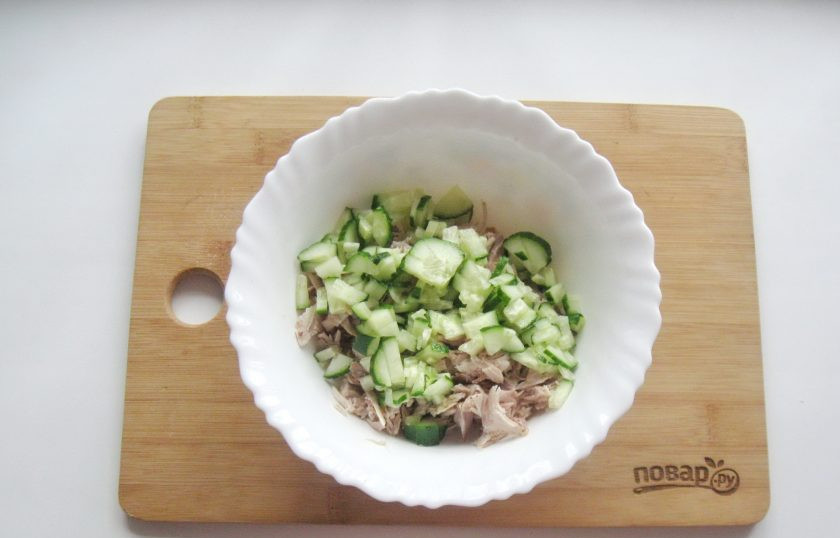 1. Этап. Салат Снежинка с курицей: Свежий огурец помойте и нарежьте кубиками. Добавьте в салат.