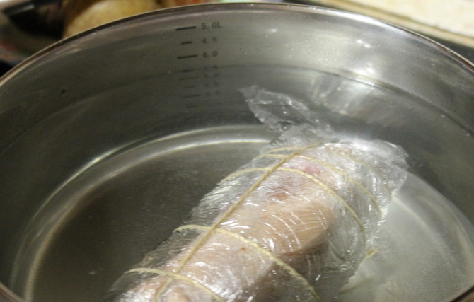1. Этап. Ветчина из рульки: Заматываем рульку в несколько слоев пищевой пленки. Заматываем плотно. Варим в кастрюле с водой в течение 2 часов на медленном огне.