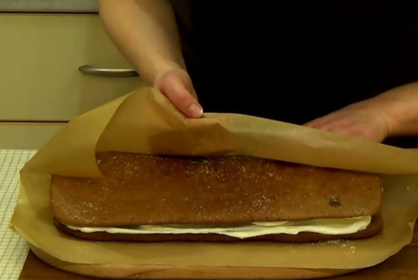 1. Этап. Торт Слеза слона: 6. В готовую помадку добавьте сливочное масло. На остывший корж нанесите крем и разровняйте. Затем выложите посредине бананы и заверните корж.