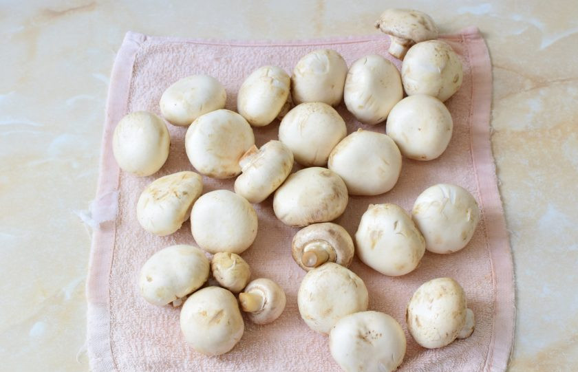 1. Этап. Шампиньоны с луком: Тщательно промойте шампиньоны от загрязнений в проточной воде. Затем выложите их на полотенце и сверху промокните другим. Оставьте грибы немного обсохнуть.