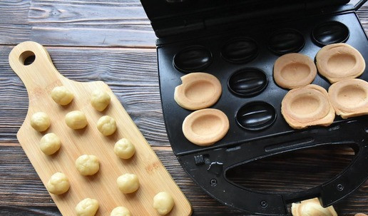 1. Этап. Закусочные орешки с тунцом и рикоттой: В бутербродницу устанавливаю панель с формочками для выпечки орешков. Разогреваю устройство. Выпекаю заготовки для орешков до подрумянивания. После чего остужаю и срезаю лишнее тесто с ореховых половинок.