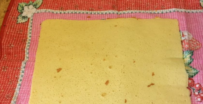 1. Этап. Бисквитный рулет со сливочно-молочным кремом: 5. Готовый бисквит слегка остудите и отрежьте края. Переложите бисквит на полотенце и вместе с полотенцем сверните в рулет. Оставьте на 20 минут.