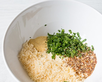 1. Этап. Куриные крылышки с сыром Пармезан в духовке: Перекладываем крылья на противень, отправляем их в разогретую до 200 градусов духовку на 40 минут. А пока пармезан трем на мелкой терке, мелко рубим петрушку и смешиваем их с чили и чесноком.