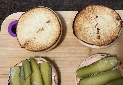 1. Этап. Чизбургер с карамелизированным луком: Для соуса майонез и кетчуп добавить в миску и хорошо перемешать. Нижнюю часть булки смазать соусом, сверху разложить нарезанные ломтики корнишонов.