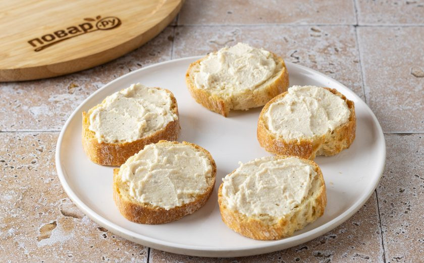 1. Этап. Брускетта с вялеными помидорами: Намажьте творожный сыр на ломтики хлеба.