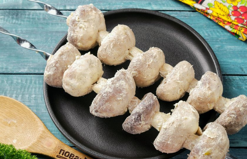 1. Этап. Сочные шампиньоны на мангале: По истечении времени, когда угли прогорят и жар станет умеренным, можно нанизывать грибы на шампуры.