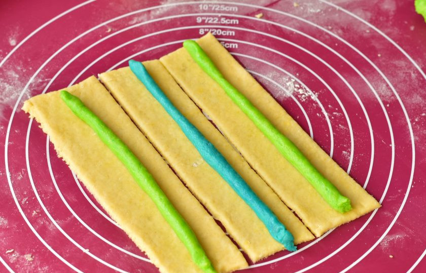 1. Этап. Печенье Карандаши: Большой кусок раскатайте скалкой, нарежьте его на прямоугольники. На каждый выложите полоску из цветного теста.