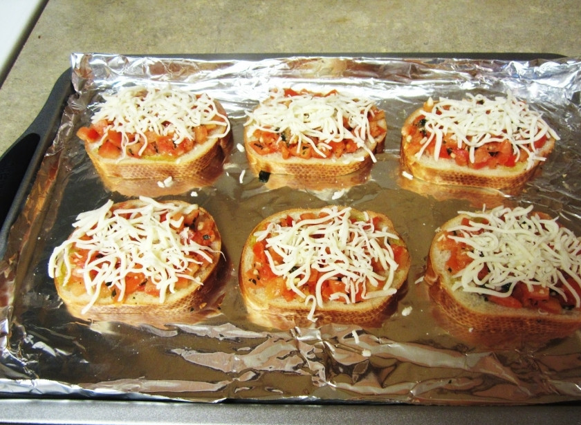 1. Этап. Бутерброды с помидорами в духовке: Натрите сыр моцарелла и посыпьте им бутерброды с помидорами.