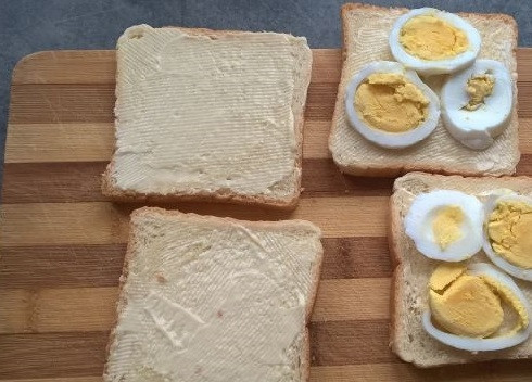 1. Этап. Бутерброды с рыбными консервами: Хлеб можно предварительно обжарить на сухой сковороде, а можно использовать и так. Смазываем ломтики тонким слоем масла. Очищенное яйцо нарезаем на довольно толстые кружочки и выкладываем на хлеб.