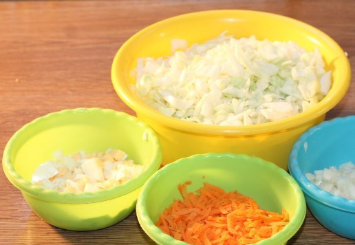 1. Этап. Круглые пирожки с овощами и яйцом: 7. Овощи и вареные яйца очищаем и нарезаем. Лук и яйцо - кубиком. Морковь трем на крупной терке. Мелко шинкуем капусту.