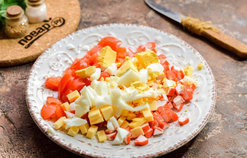 1. Этап. Салат с крабовыми палочками и маринованным луком: Очистите вареное яйцо и нарежьте небольшими кубиками. Добавьте яйцо в салат.