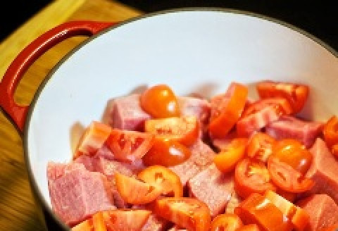 1. Этап. Мясо, тушенное в духовке: Помидоры вымыть, нарезать дольками и выложить в кастрюлю к мясу.