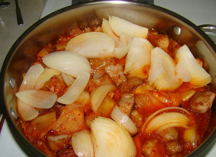 1. Этап. Кимчи со свининой: 4. Откройте крышку. Продолжайте жарить, пока не выпарится вся жидкость и не останется только жир. В почти приготовленное блюдо добавьте измельченный чеснок. Перемешайте. Выключите огонь. Блюдо готово. Подавайте со свежими овощами, рисом, зеленью.