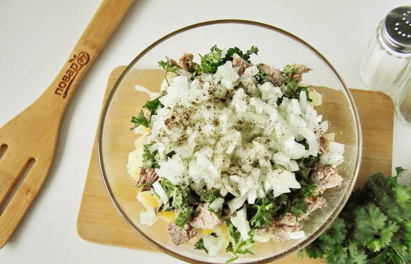 1. Этап. Рыбный салат из консервов с картошкой: Лук нарежьте кубиками, обдайте кипятком, чтобы ушла горечь и слега отожмите. Вместе с луком добавьте в салат масло, соль и молотый перец.