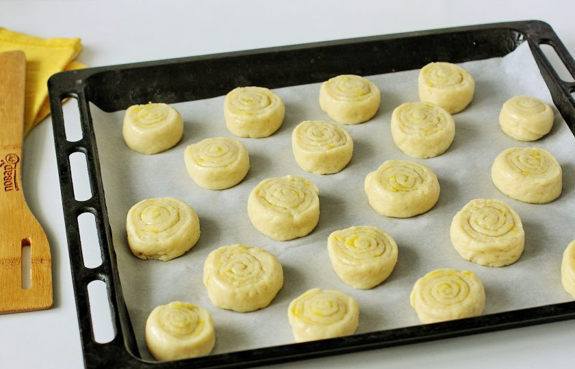 1. Этап. Лимонное печенье на кефире: Нарежьте рулет кусочками, шириной 2-3 см. и переложите заготовки на противень застеленный пергаментом. Сверху каждый рулетик прижмите немного руками. Выпекайте в духовке при температуре 180 градусов до легкого подрумянивания.