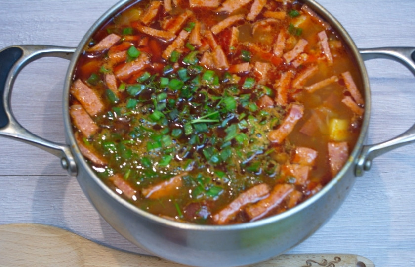 1. Этап. Суп солянка сборная мясная: Томатно-мясную зажарку переложите в кастрюлю с кипящим картофельным отваром. Перемешайте. Дайте повариться 5 минут. Теперь переложите в кастрюлю отдельно варившиеся огурцы вместе с водой. Варите еще 10 минут. Добавьте измельченную зелень в самом конце варки.