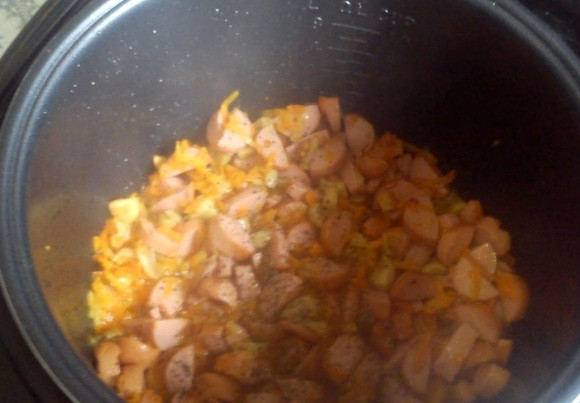 1. Этап. Картофель с сосисками в мультиварке: После этого добавляем тертую на крупной терке морковку, продолжаем все жарить, а через 3-5 минут добавляем нарезанные кружочками сосиски. Посыпаем все специями по вкусу, перемешиваем и 8-10 минут готовим все вместе.