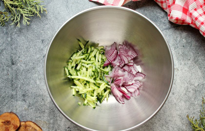 1. Этап. Салат из редьки с жареным мясом: Свежий огурец порежьте средней соломкой, красный лук полукольцами. Выложите овощи в салатник.