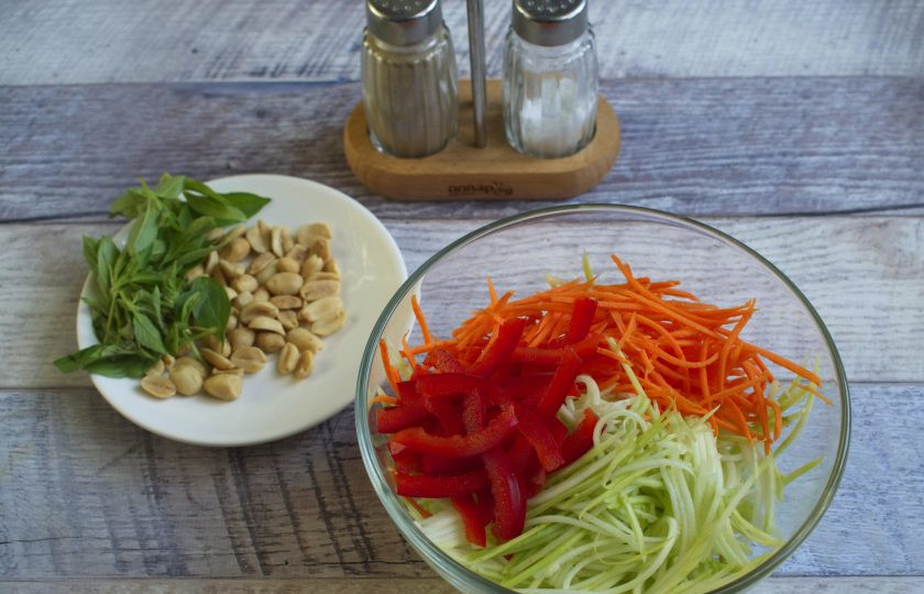 1. Этап. Морковно-кабачковая паста: Перец нарежьте тонкой соломкой, кабачок и морковь натрите на терке для корейской морковки. Базилик измельчите. Добавьте арахис. Посолите и перемешайте.