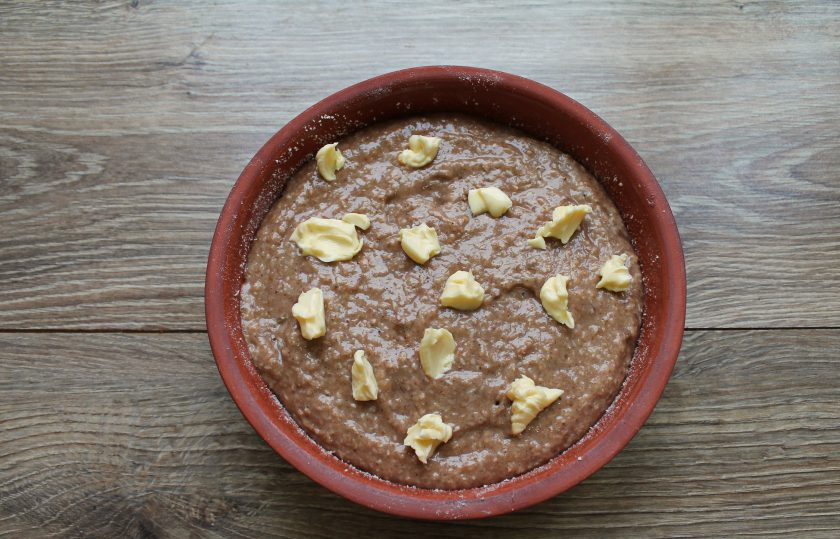 1. Этап. Кето-шарлотка с яблоками: Вылейте оставшееся тесто поверх яблок и разровняйте. Распределите масло маленькими кусочками на поверхности теста.