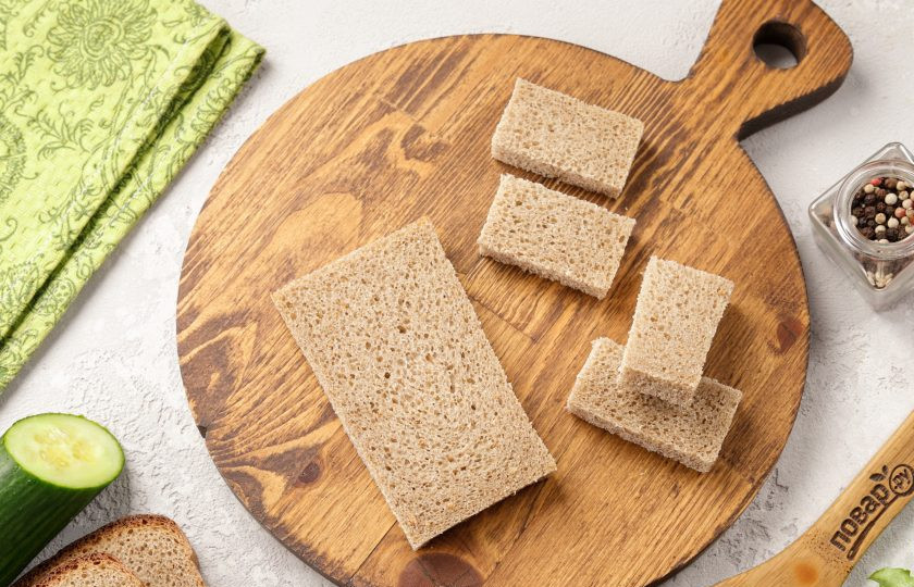 1. Этап. Канапе со шпротами и огурцом: Разрежьте хлеб на 2 или 4 части, в зависимости от размера. По желанию можете обжарить кусочки на сковороде или подсушить в духовке.