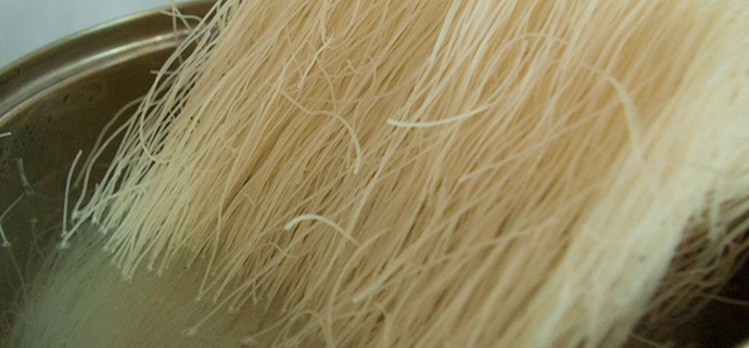 1. Этап. Рисовая лапша с овощами и курицей: Пока тушатся овощи с курицей, налейте в кастрюльку чистой воды, закипятите ее. В кипяток опустите рисовую лапшу на несколько минут, затем откиньте ее на дуршлаг.