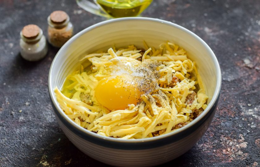 1. Этап. Гречневые котлеты с сыром: Вбейте в миску куриное яйцо, добавьте соль и перец.