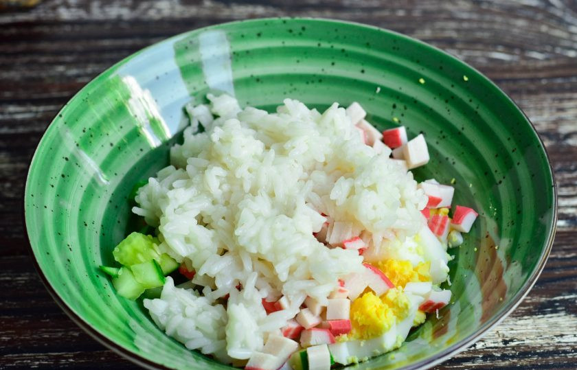 1. Этап. Салат с крабовым мясом по ГОСТу: Выложите все нарезанные ингредиенты в миску. Рис отварите, остудите и добавьте в миску.