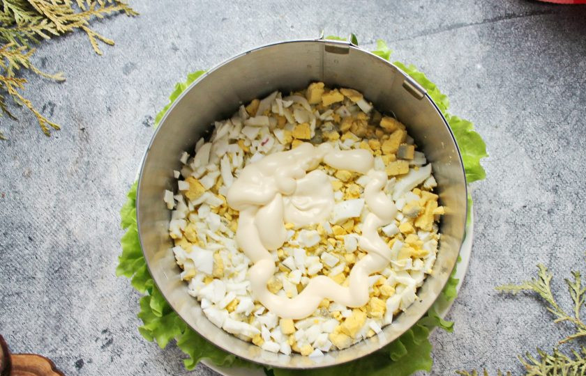 1. Этап. Салат с красной рыбой и креветками слоями: Отварные яйца почистите и порежьте мелким кубиком. Выложите яйца на картофель, примните и смажьте майонезом.