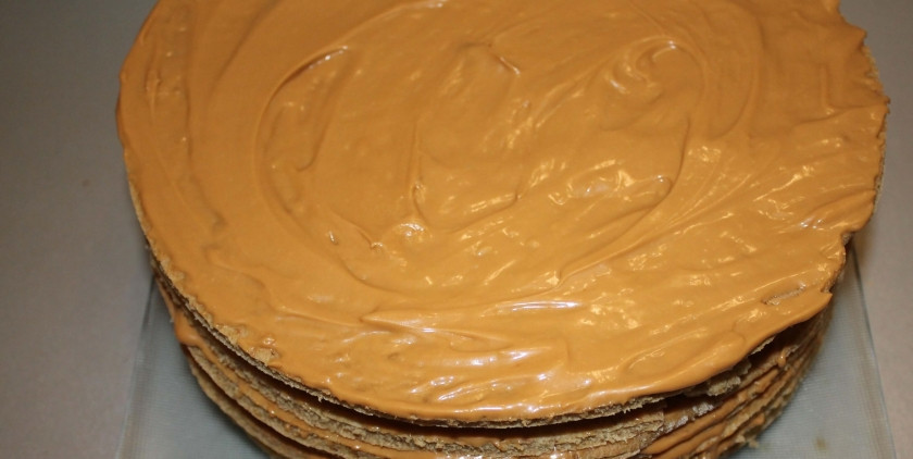 1. Этап. Медовик со сгущенкой: 6. Для крема: в миску выкладываю размягченное сливочное масло, миксером взбиваю его до образования пышной массы, затем струйкой ввожу вареное сгущенное молоко, продолжаю взбивать до образования однородной массы. Каждый пласт щедро промазываю получившимся кремом и складываю их один на другой.