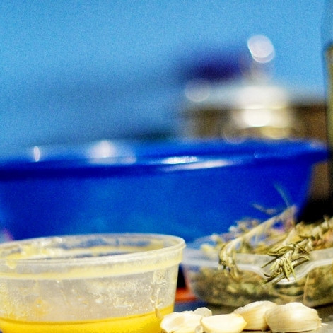 1. Этап. Кролик на гриле: Приготовим маринад. В ступке измельчаем листья свежего розмарина и тимьяна, чеснок. Добавляем оливковое масло, мед, сок и цедру одного лимона.